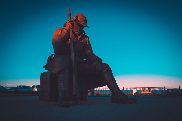 Statue against clear blue sky in city during sunset
