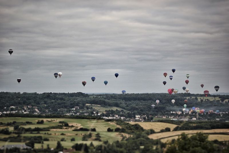 Hot air balloons flying in the bristol balloon fiesta against cloudy sky