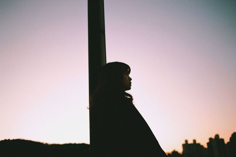 Silhouette of woman against sky at sunset