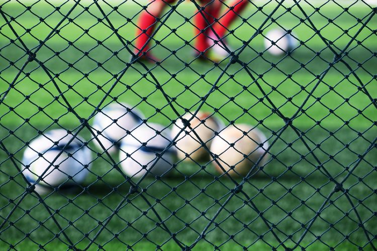Low section of soccer players playing on field seen through net