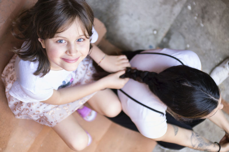 High angle portrait of smiling girl tying mother hair