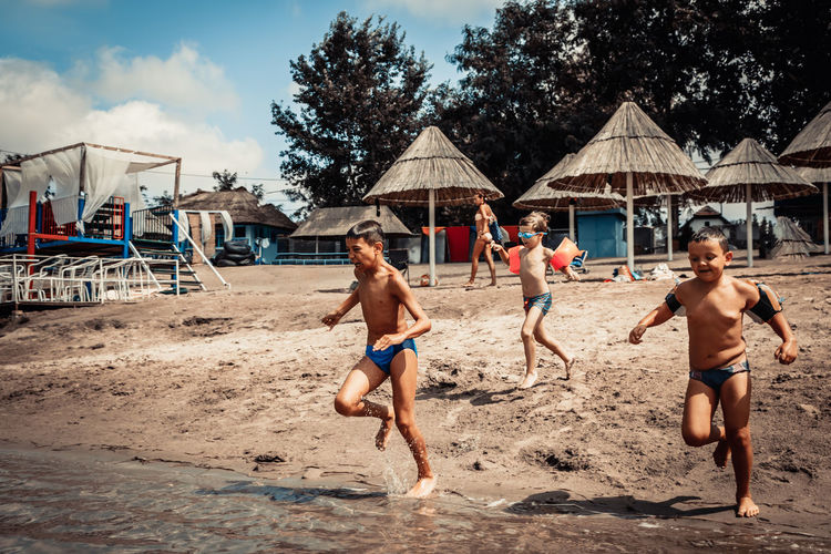 Group of happy kids running on the beach and having fun in summer day.