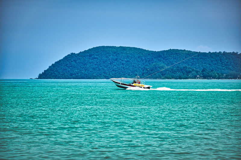 Speed boat on the waves of the azure andaman sea under the blue sky near the sandy beachshore