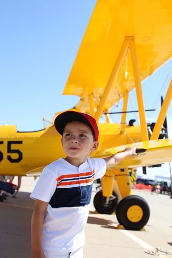 Boy standing against yellow plane