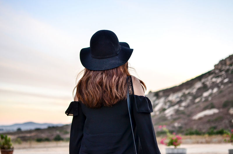 Rear view of woman wearing hat standing against sky