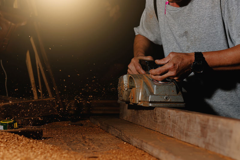 Close-up of a carpenter using a circular saw or a tool to cut wooden planks to make furniture  