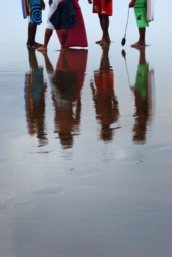 Low section of people walking on wet beach