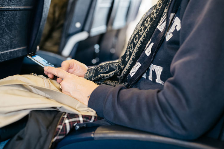 Midsection of woman using smart phone sitting in bus
