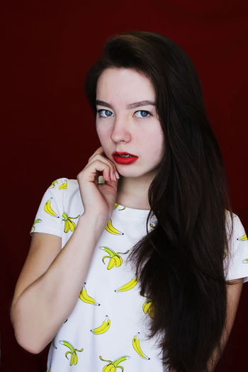 Portrait of beautiful young woman against maroon wall