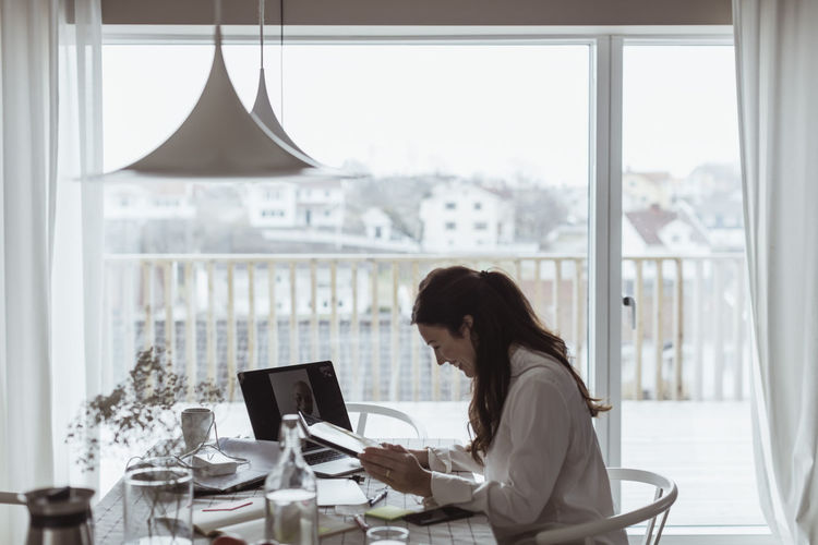 Smiling businesswoman on video call with male colleague at home office during pandemic