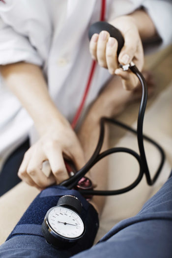Cropped image of female doctor taking patient's blood pressure at clinic