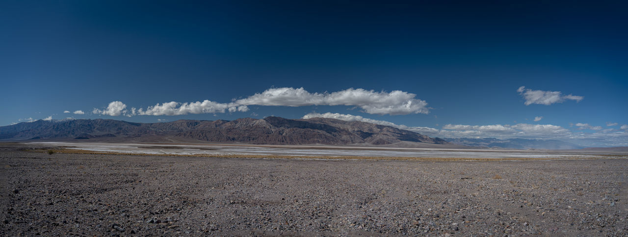 Scenic view of arid landscape against blue sky