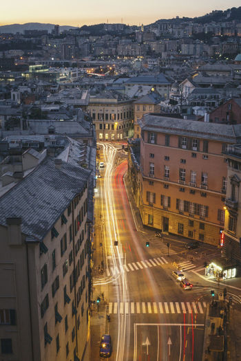 Scenic view of city at dusk with light trails in the street amidst buildings