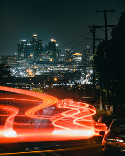 Light trails on street against illuminated buildings in city at night