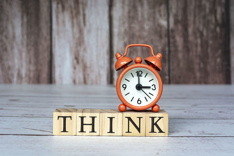 Think text on wooden blocks and alarm clock set at 3 o'clock on table. business and idea concept.