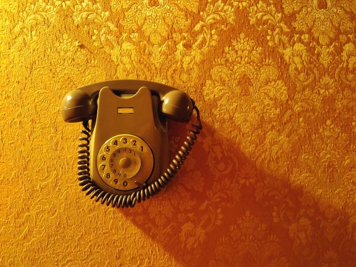 Close-up of telephone over yellow wall