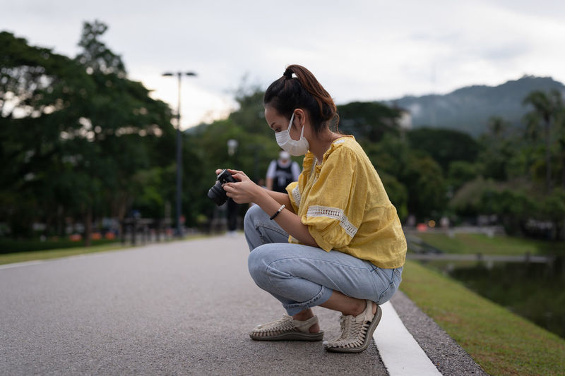 Series photo of young women wearing surgical protection mask playing with camera in the evening