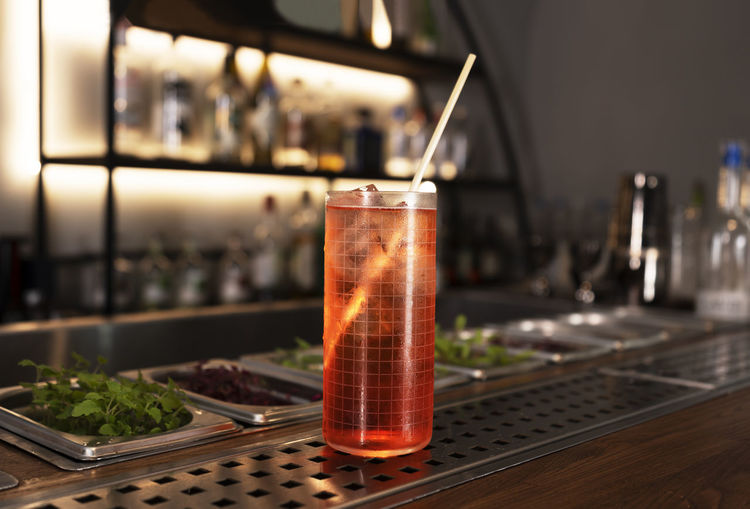 A glass of red alcohol drink with a cocktail tube on a bar counter. night club drink.