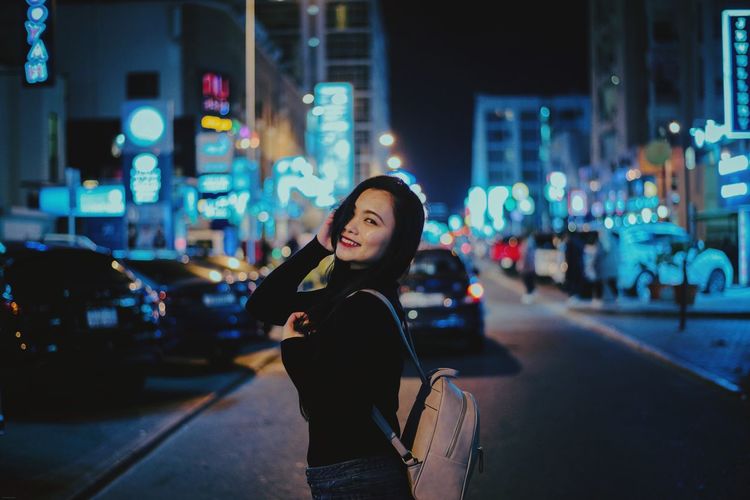 Young woman standing on city street at night