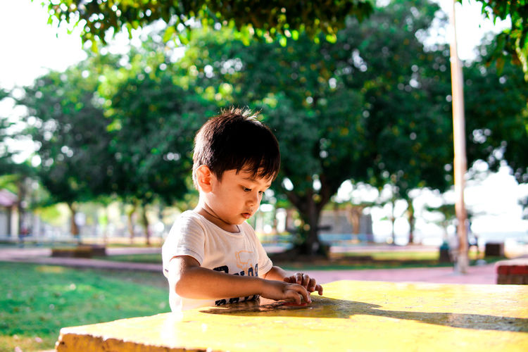 A young boy playing alone on a table at a park