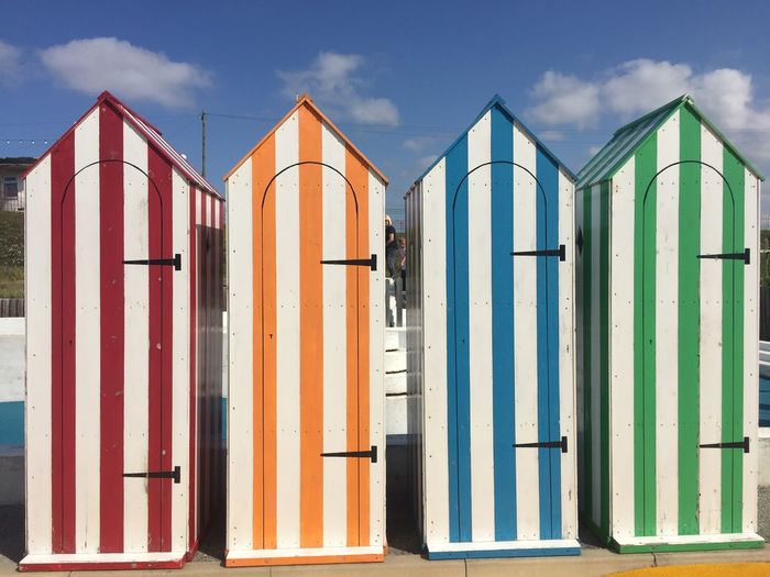 Panoramic view of beach huts against buildings against sky
