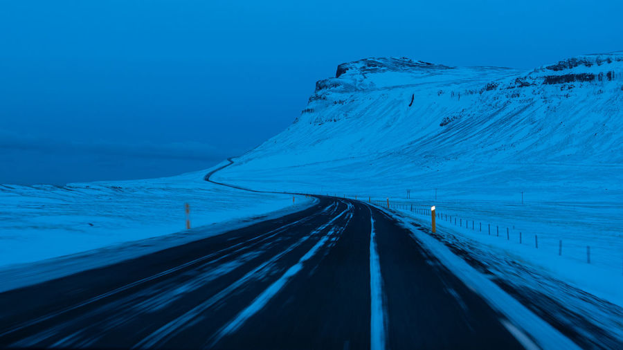 Winter road with snowy mountain during blue hour