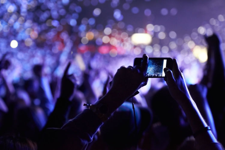 Cropped image of man photographing at music concert