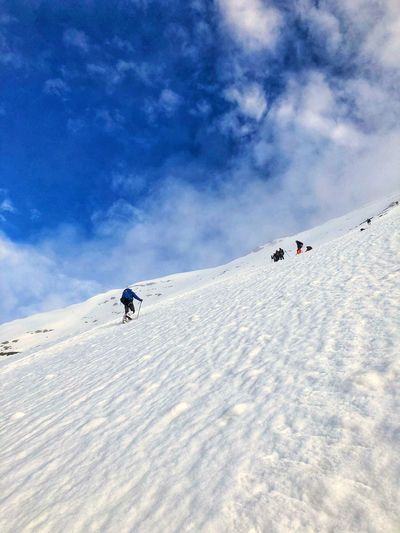 People skiing on snow covered mountain against sky