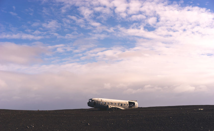 Crashed airplane on landscape against clouds