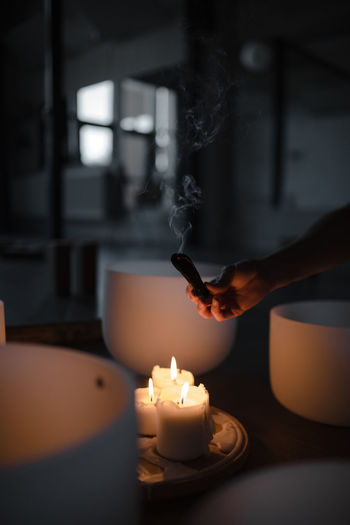 Woman hand holding herb bundle of dried sage smudge stick smoking
