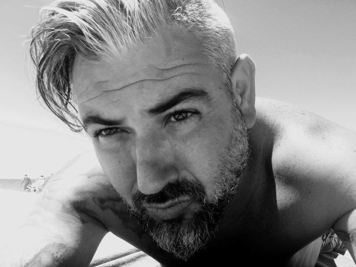 Close-up portrait of shirtless mature man lying at beach