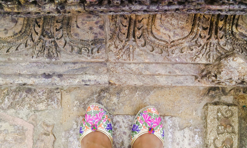 Low section of woman standing on floor of beautiful carved rock at sun temple, konark
