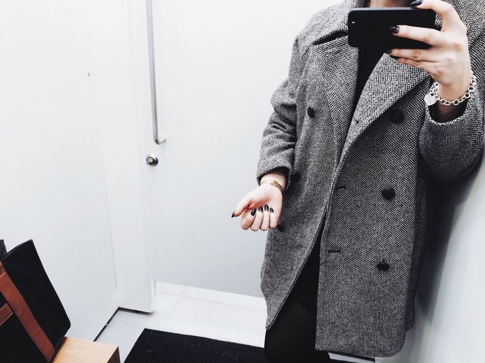 Midsection of woman photographing in front of mirror
