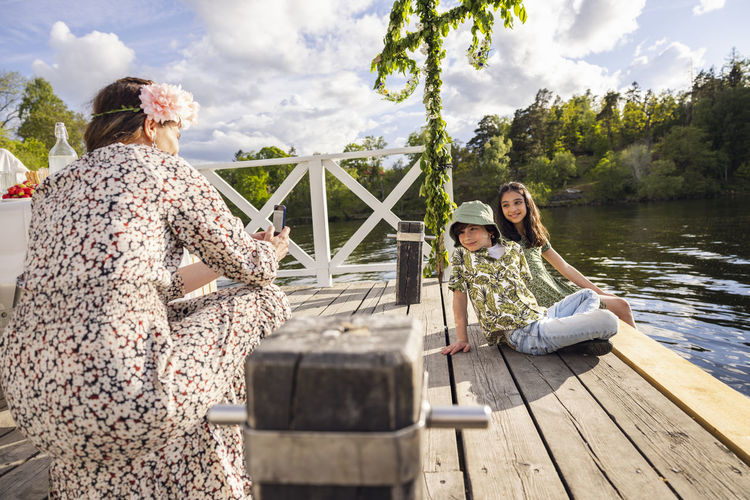 Side view of woman sitting on pier over lake