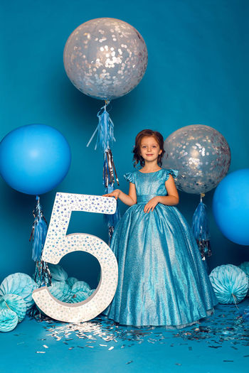 Girl in the blue dress in the studio with the balloon and with the number five