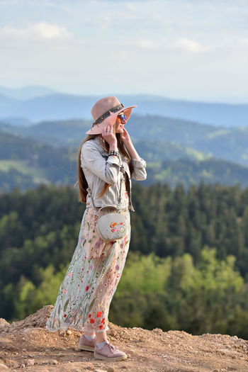 Full length of woman wearing hat and sunglasses while standing against mountain