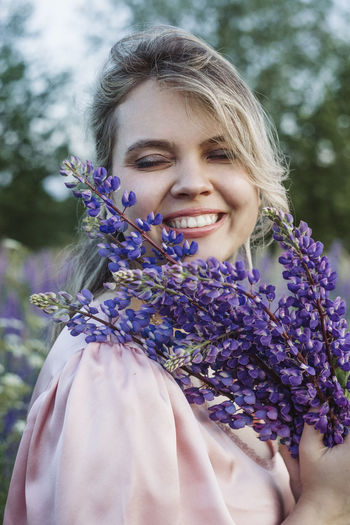 Portrait of a smiling young woman against purple flowering plants