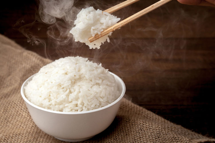 Eating rice by using chopsticks on wooden background