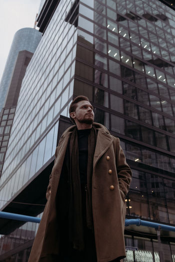 Low angle view of man standing against modern building in city