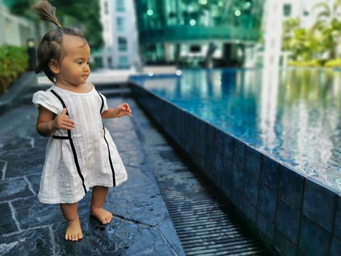 Full length of baby girl standing infront of swimming pool