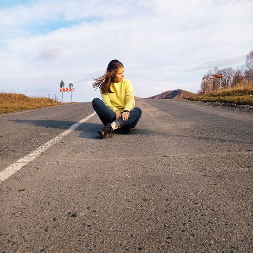 Full length of woman sitting on road