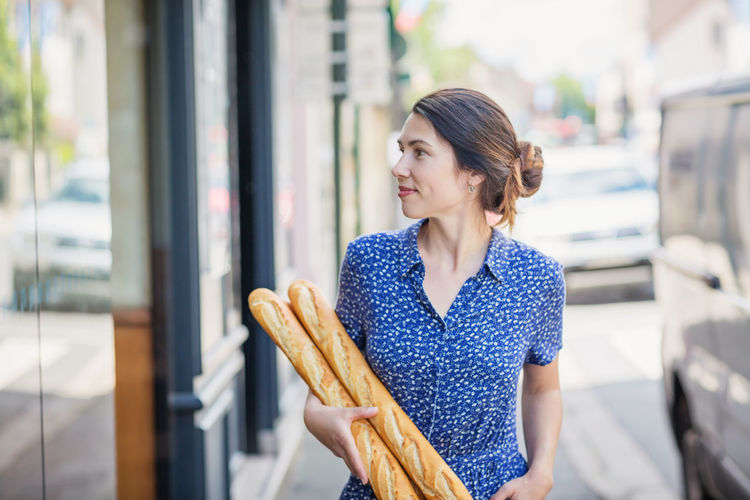 Young woman buying a french baguette