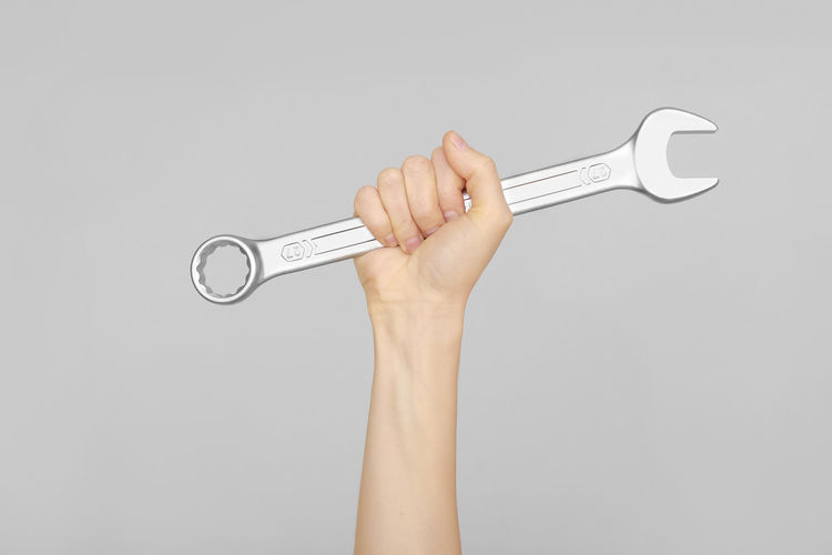 Cropped image of hand holding key against white background