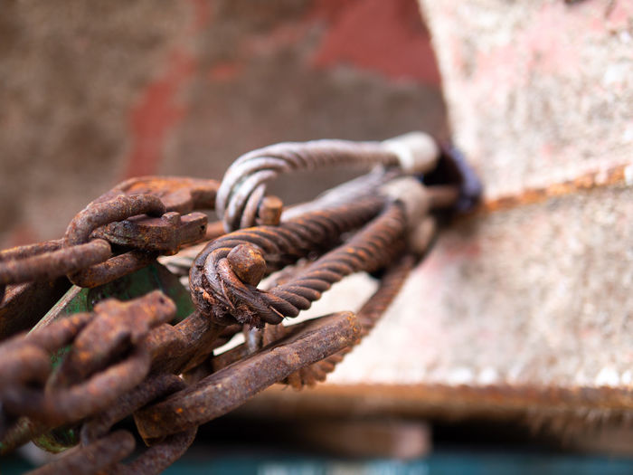 Close-up of rusty chain tied up on metal