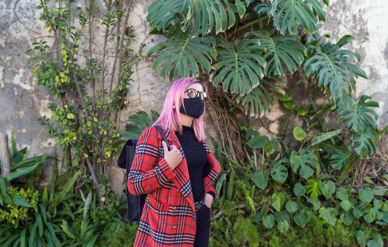Traveler woman with mask in protection to the pandemic observes
the exotic travel vegetation