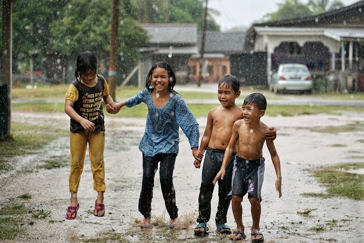 Full length of children on water during rainy season