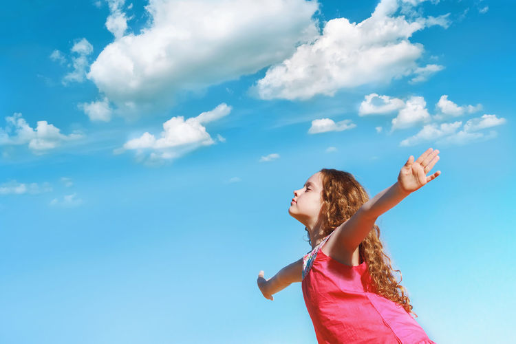 Little girl outstretched arms and closed her eyes enjoying and breath fresh air.