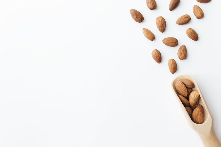 Raw almond kernels in wooden spoon on white background. cosmetic and healthy food concept