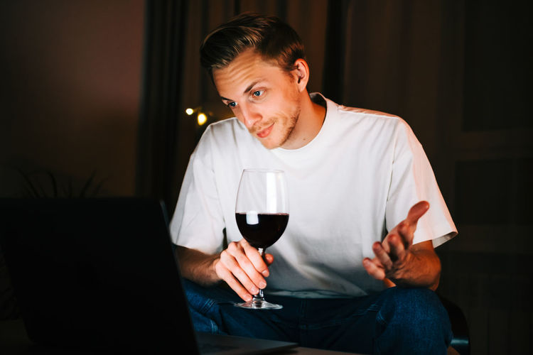 Young man drinking glass on table at home