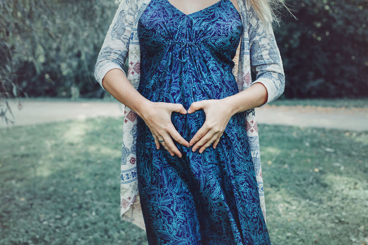 Midsection of pregnant woman making heart shape with hands